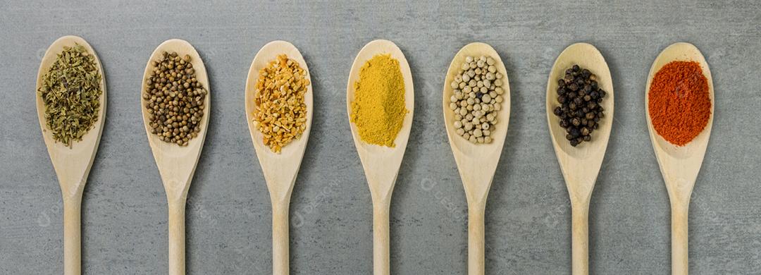 Várias especiarias em colheres de madeira lado a lado vistas de cima
