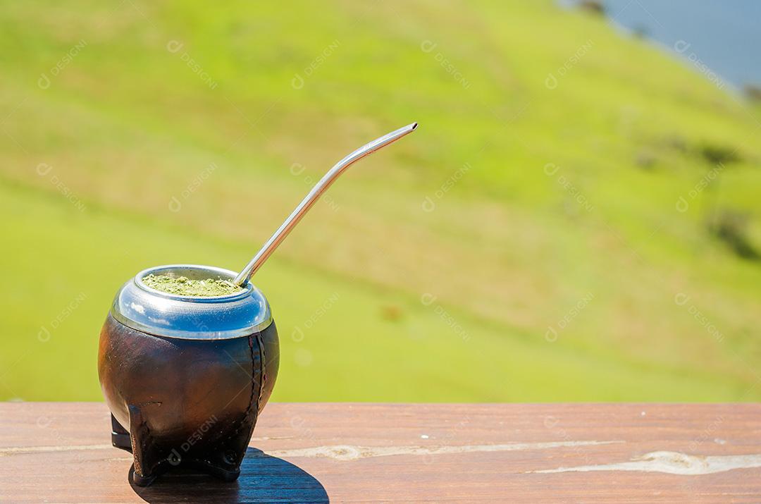 Mate tradicional, mate, com vista de campo verde. (Chimarrão).