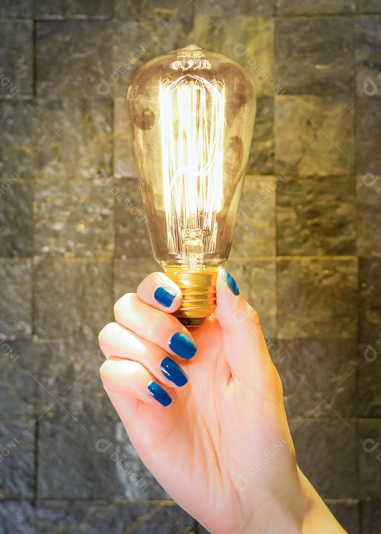 Excelente conceito de ideia, mão feminina segurando lâmpada acesa clássica.