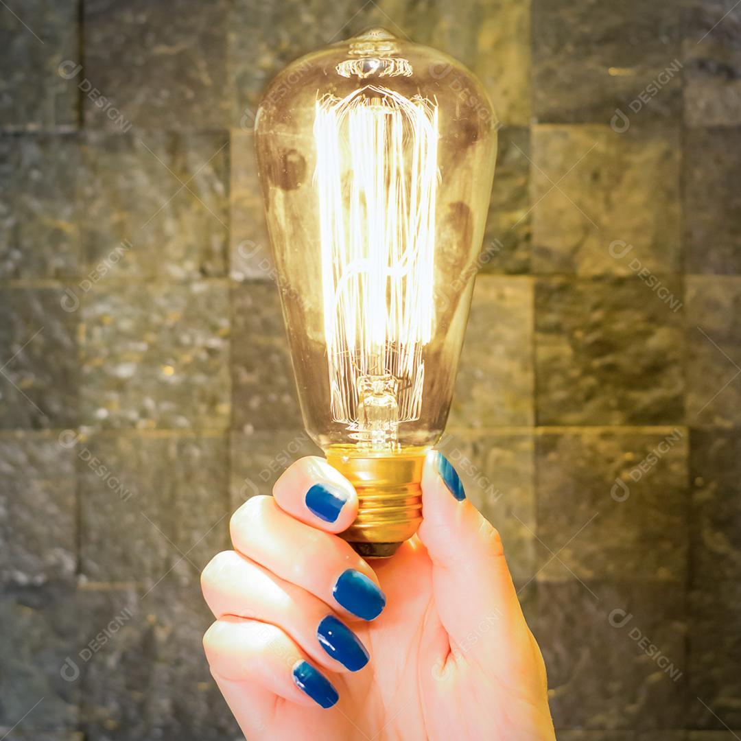 Excelente conceito de ideia, mão feminina segurando lâmpada acesa clássica.
