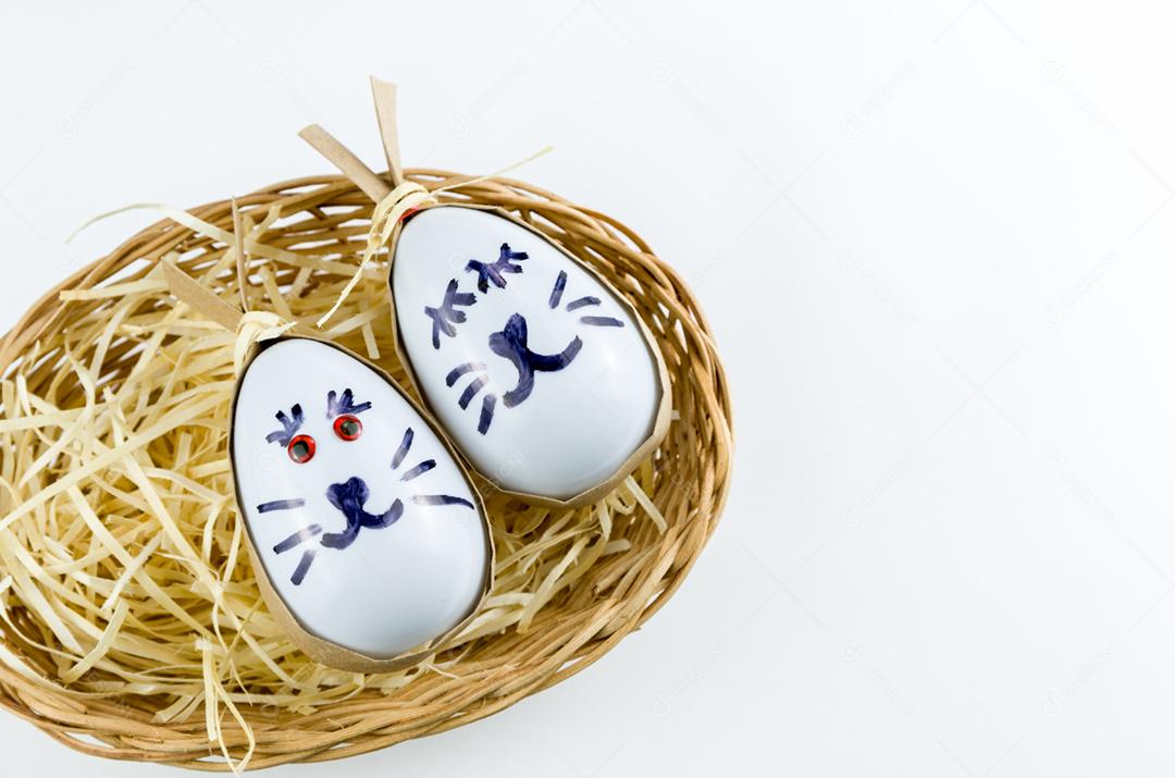 Ovo de coelhinho da páscoa feliz e ovos coloridos em uma cesta isolada em um fundo branco na moda