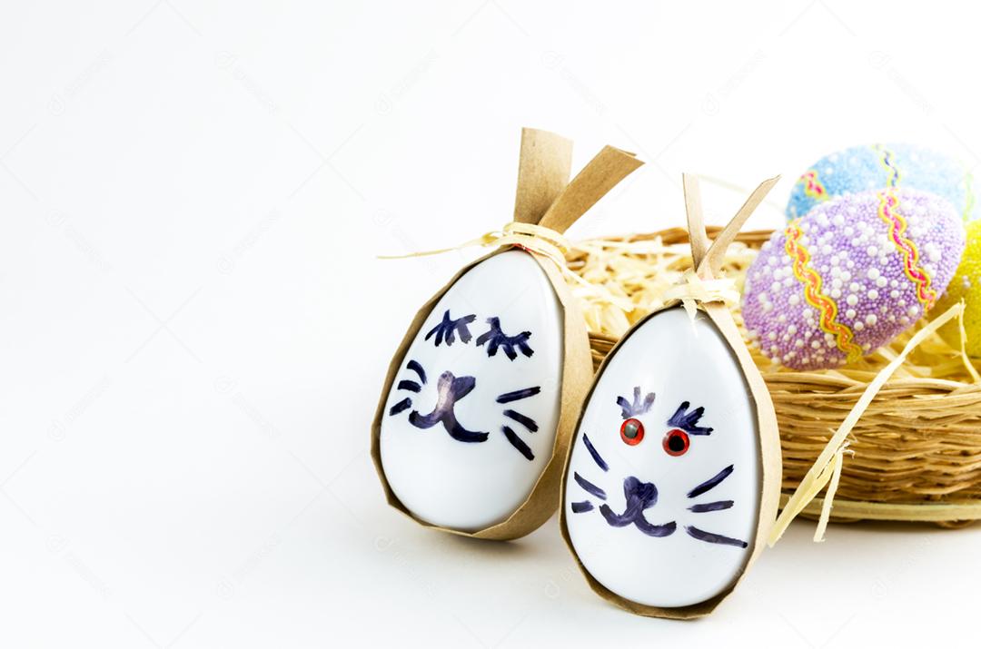 Ovo de coelhinho da páscoa feliz e ovos coloridos em uma cesta isolada em um fundo branco na moda
