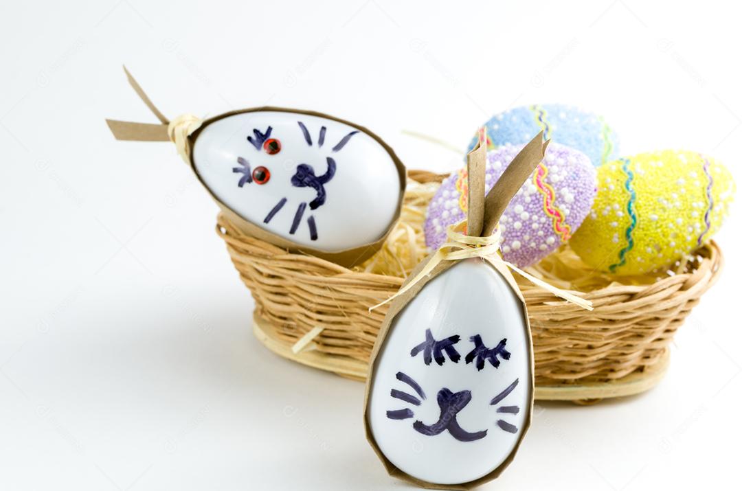 Ovo de coelhinho da páscoa feliz e ovos coloridos em uma cesta isolada em um fundo branco na moda