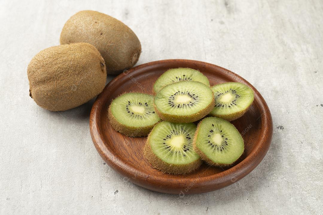 Dois kiwis com fatias em uma tábua de madeira