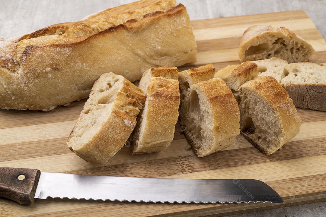 Tradicional pão de baguete francês caseiro com fatias sobre madeira