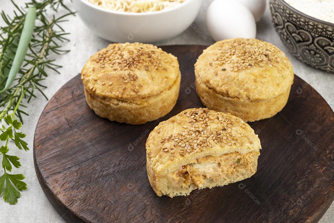 Tortas de frango caseiras sobre tábua de madeira com ingredientes