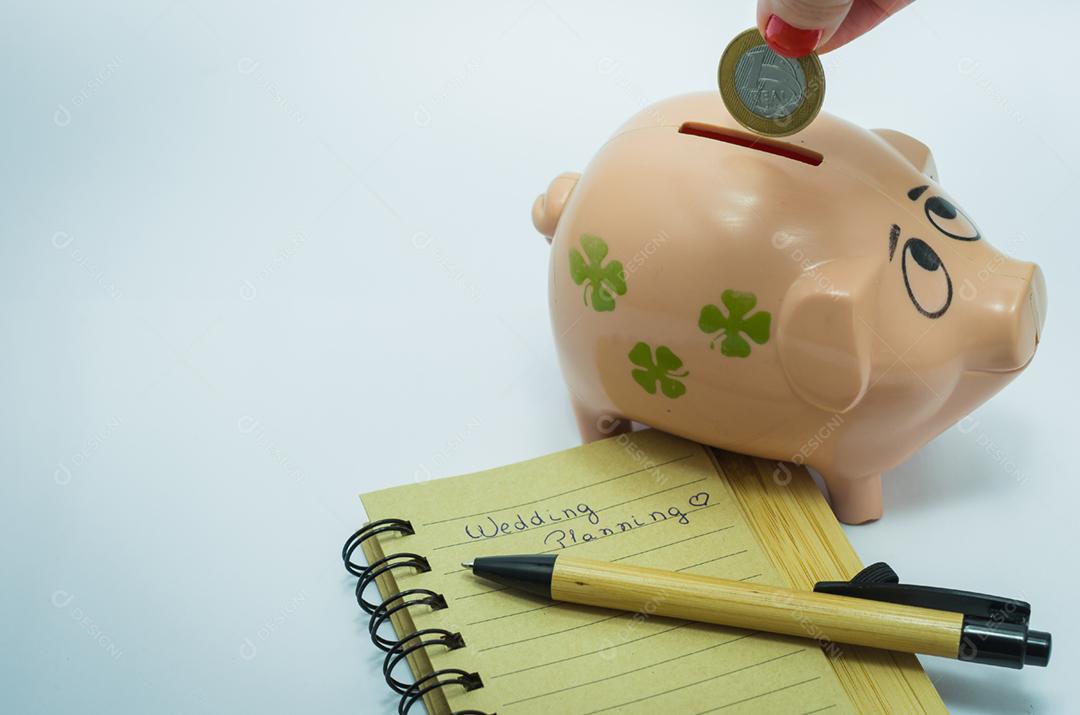 Grande conceito de economia para férias, inserindo moeda brasileira no cofrinho, moeda real, caderno e caneta.