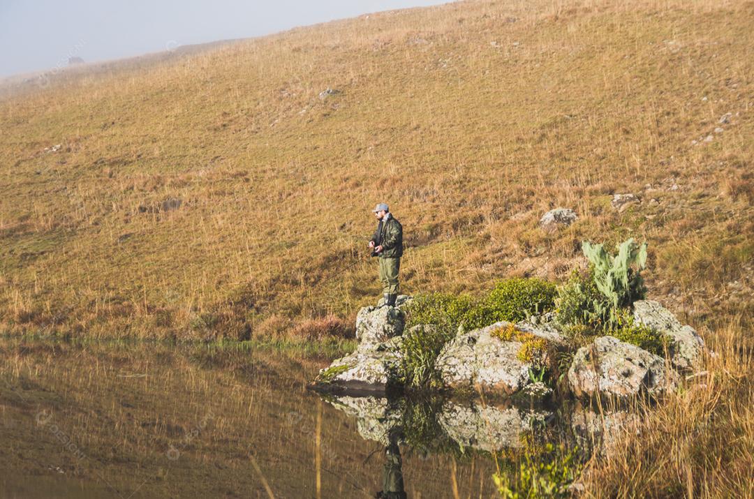 Pescador esportivo de pesca no lago em dia nublado