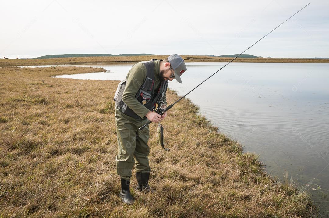 Pescador esportivo de pesca no lago em dia nublado