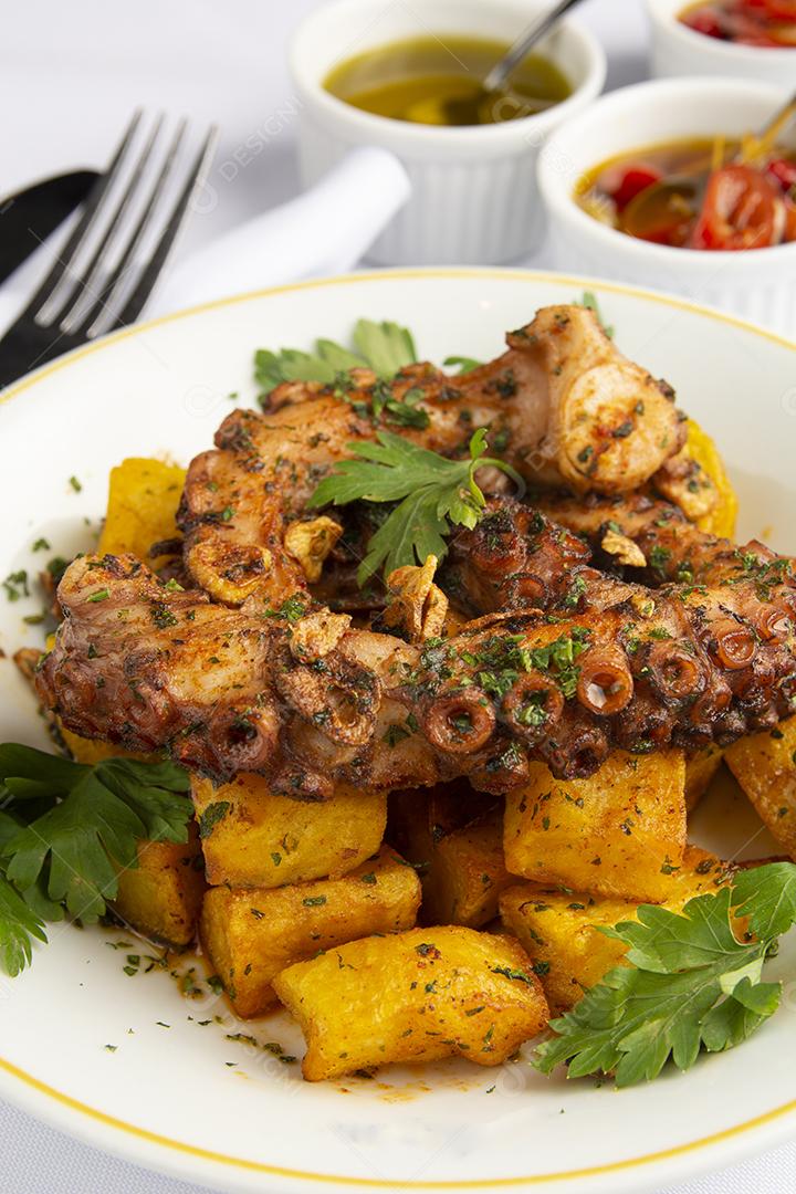 Polvo grelhado e batatas sobre um prato branco em um espanhol