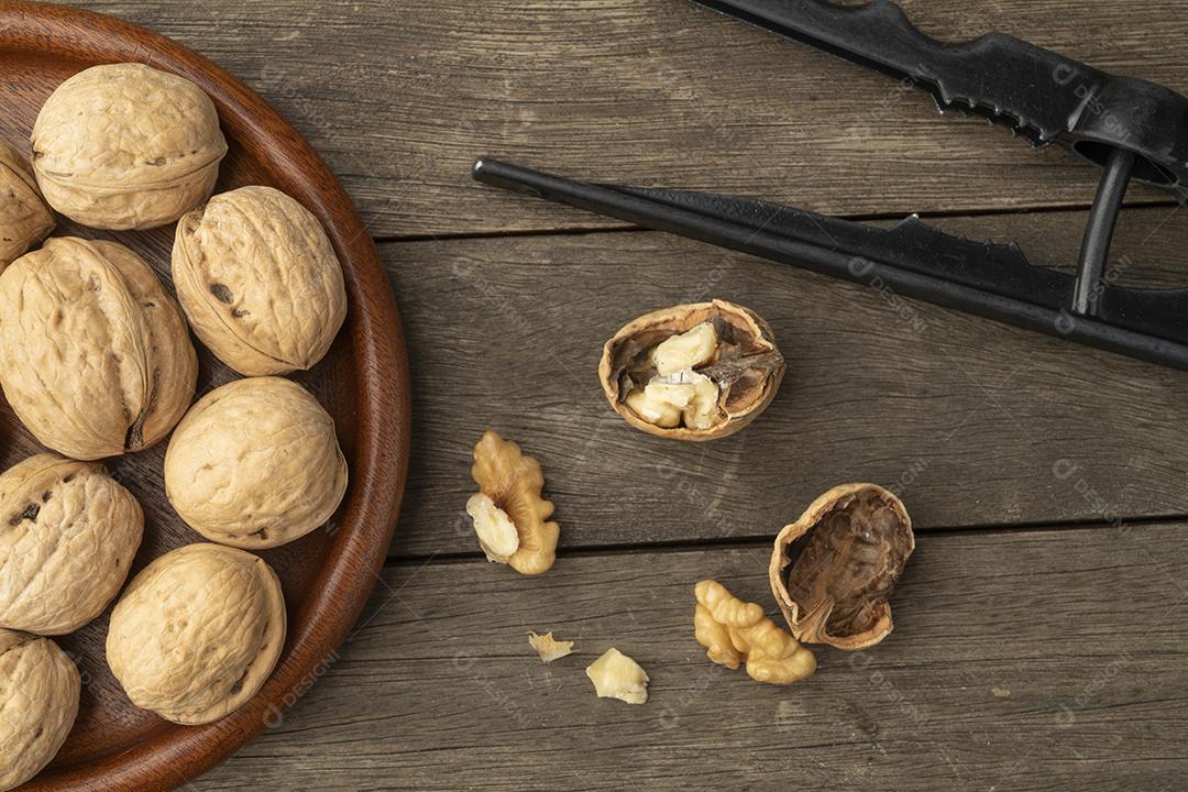 Nozes, biscoito de nozes e nozes rachadas sobre mesa de madeira