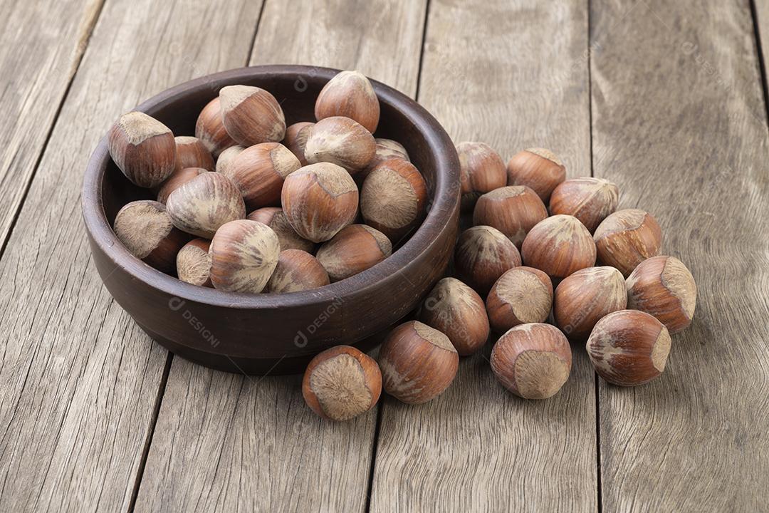 Um grupo de avelãs em uma tigela sobre mesa de madeira
