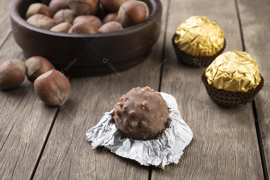 Chocolates recheados de avelãs e avelãs sobre mesa de madeira