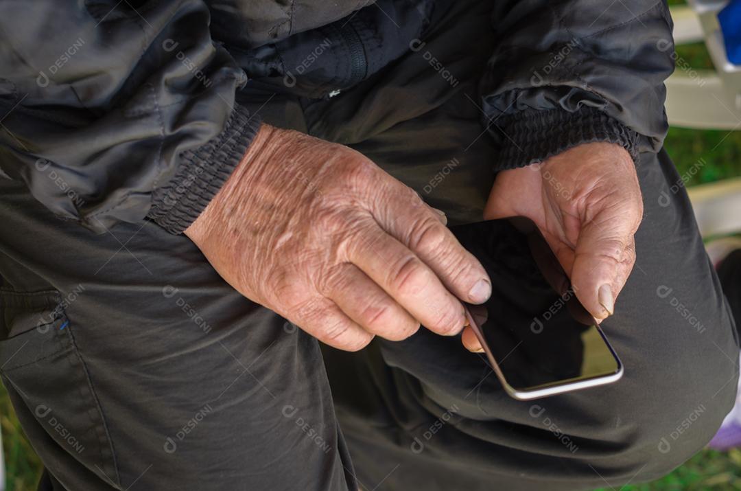 Dedo enrugado de um homem, tocando em um telefone celular