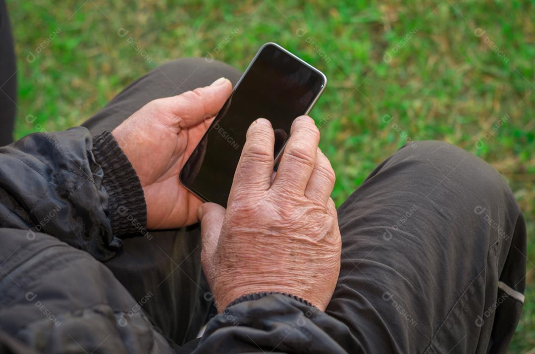 Dedo enrugado de um homem, tocando em um telefone celular
