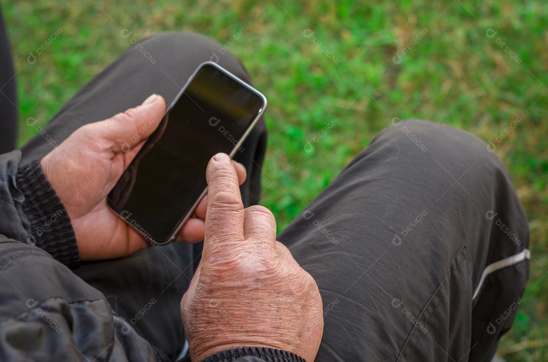 Dedo enrugado de um homem, tocando em um telefone celular