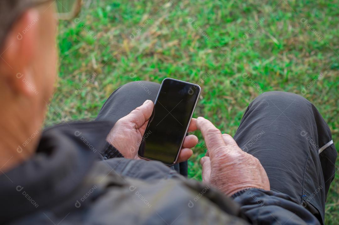 Dedo enrugado de um homem, tocando em um telefone celular