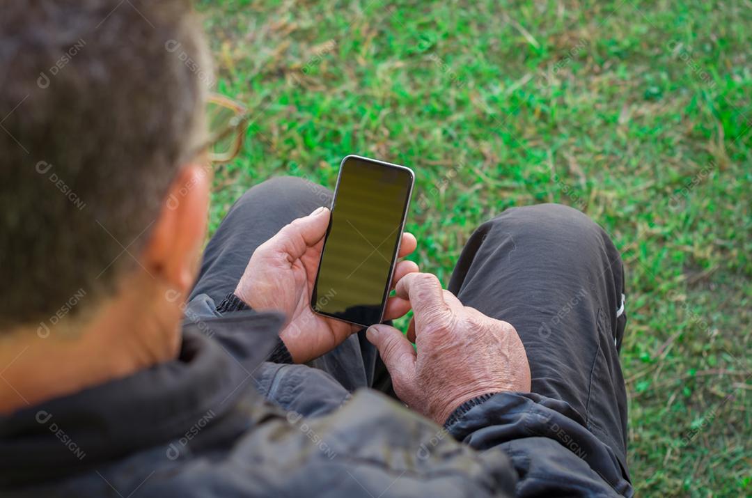 Dedo enrugado de um homem, tocando em um telefone celular