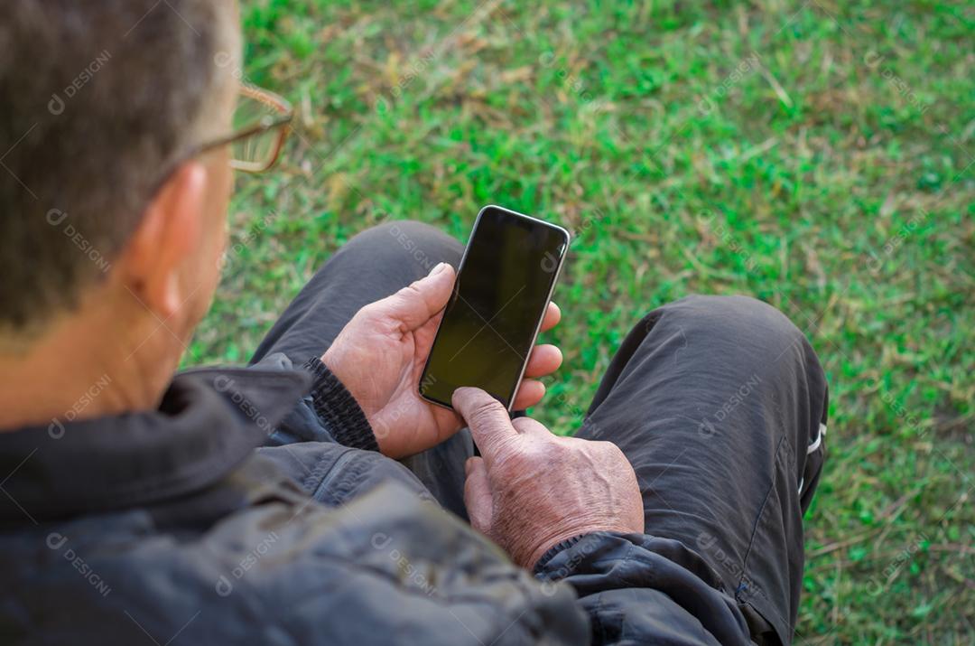 Dedo enrugado de um homem, tocando em um telefone celular