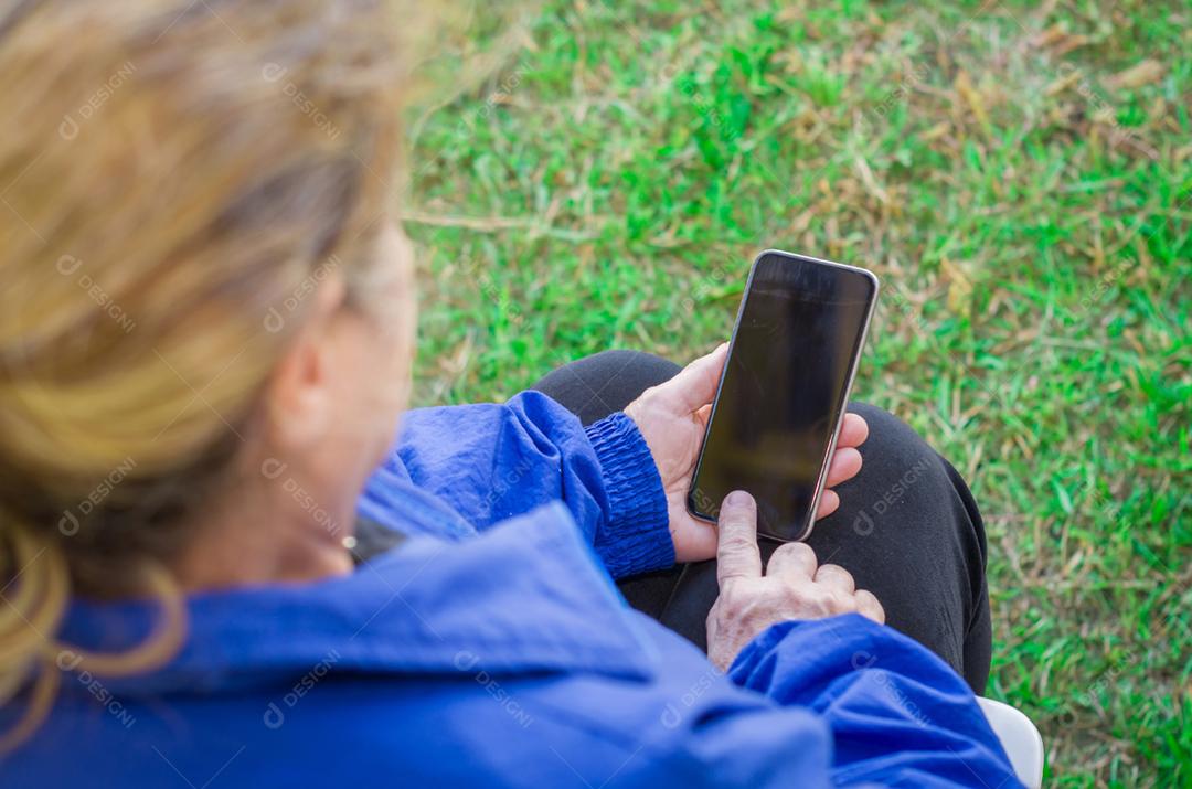Dedo enrugado de um mulher, tocando em um telefone celular