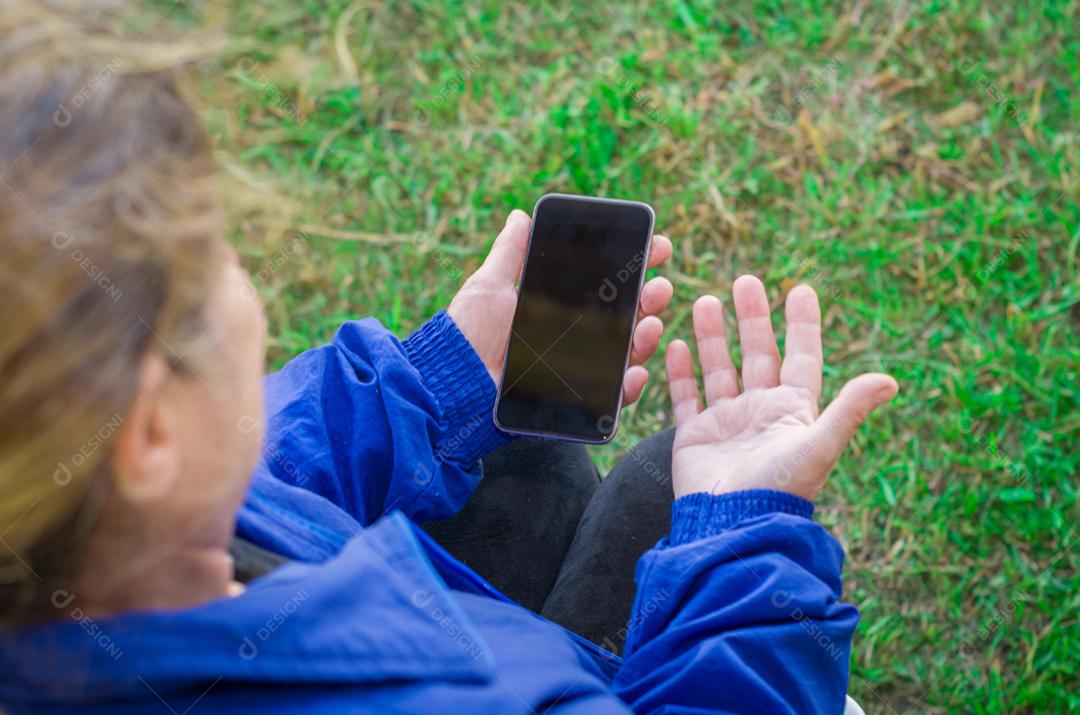 Dedo enrugado de um mulher, tocando em um telefone celular