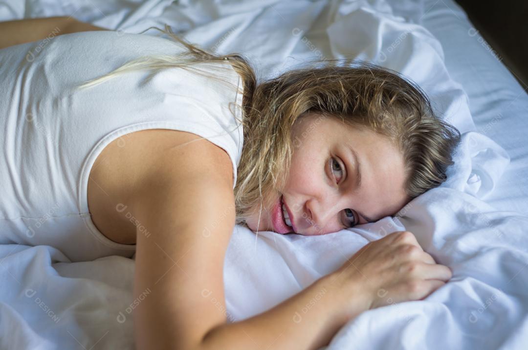 Jovem mulher linda deitado em uma cama lençol branco