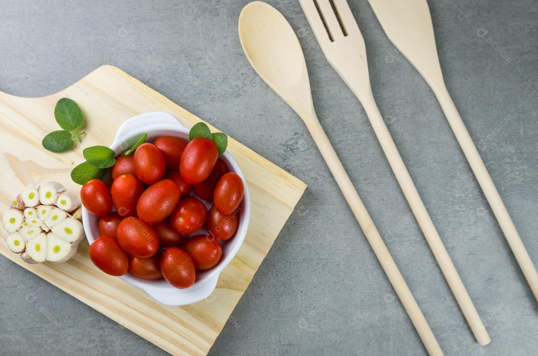 Placa de madeira com tomate cereja em fundo cinza. fundo culinário.