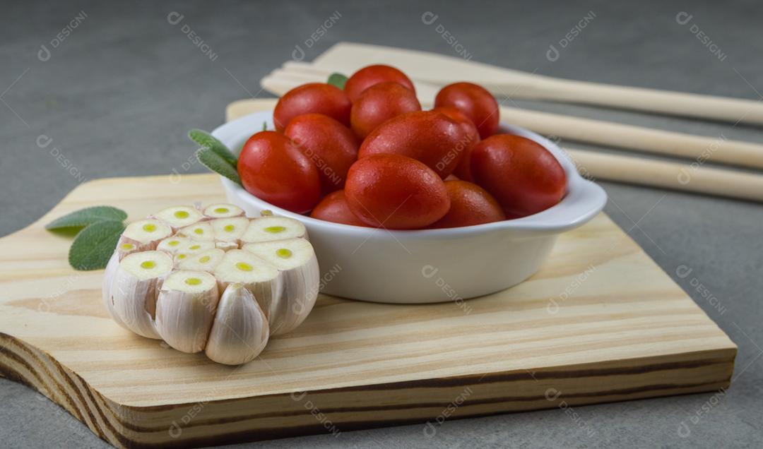 Placa de madeira com tomate cereja em fundo cinza. fundo culinário.