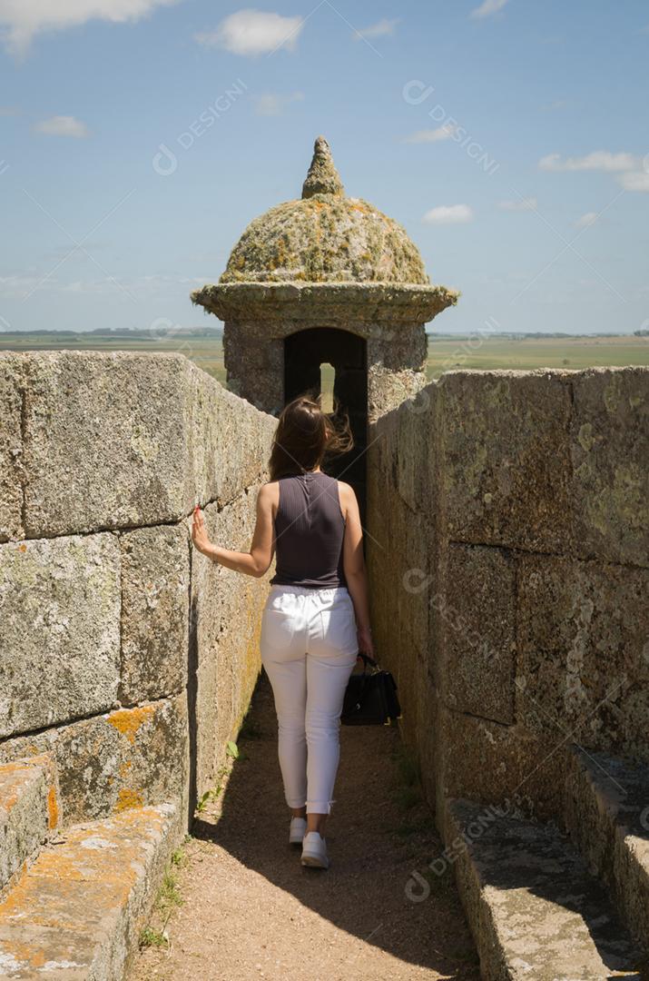 Jovem olhando Forte de Santa Tereza no Uruguai, importante local turístico.