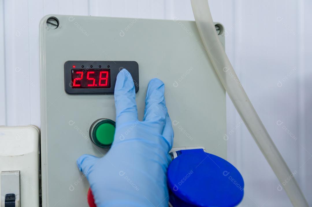 Mulher que trabalha na indústria, ajustando o termostato do tanque