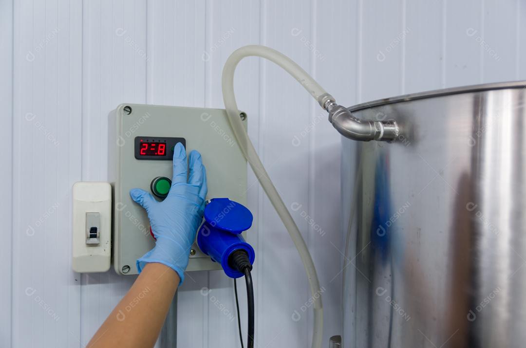 Mulher que trabalha na indústria, ajustando o termostato do tanque