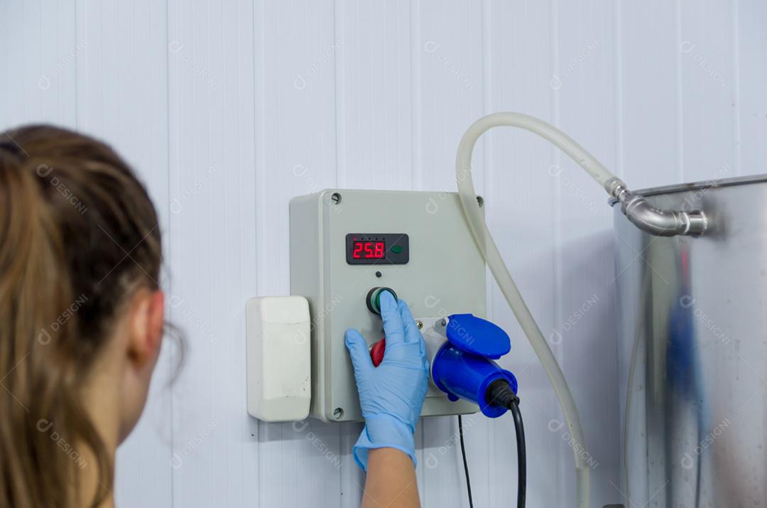 Mulher que trabalha na indústria, ajustando o termostato do tanque