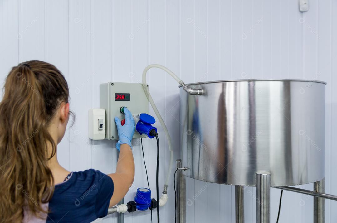 Mulher que trabalha na indústria, ajustando o termostato do tanque