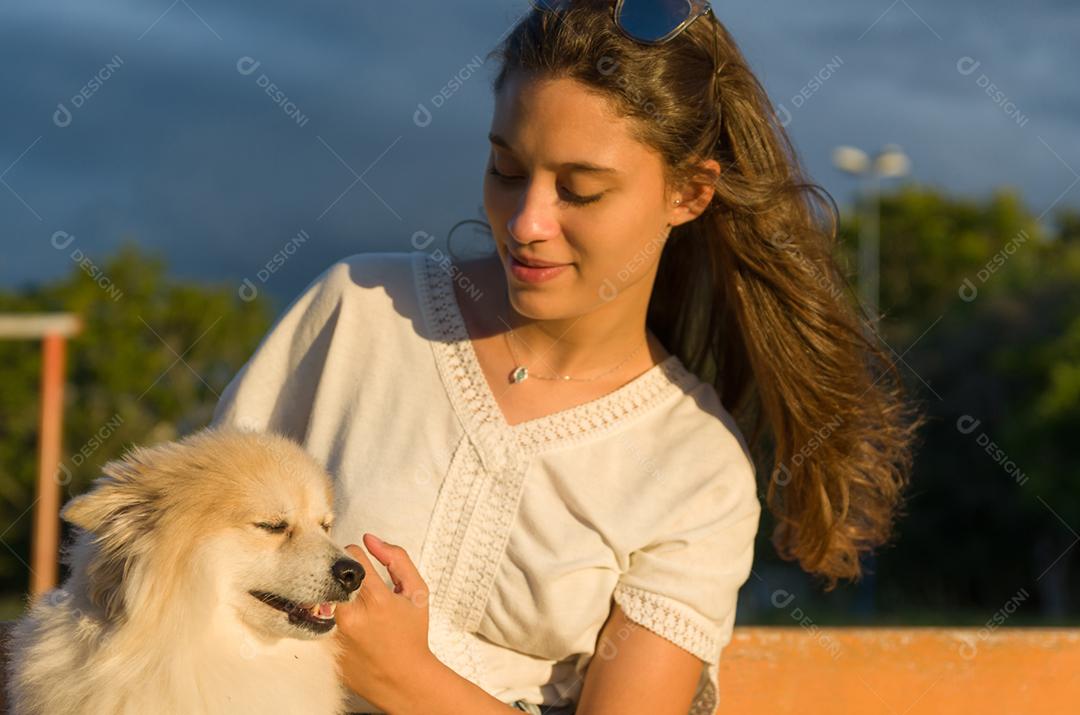 Jovem mulher bonita brincando com cachorro Spitz alemão no parque de verão