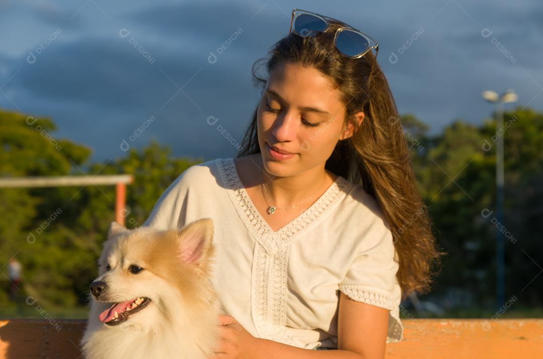 Jovem mulher bonita brincando com cachorro Spitz alemão no parque de verão