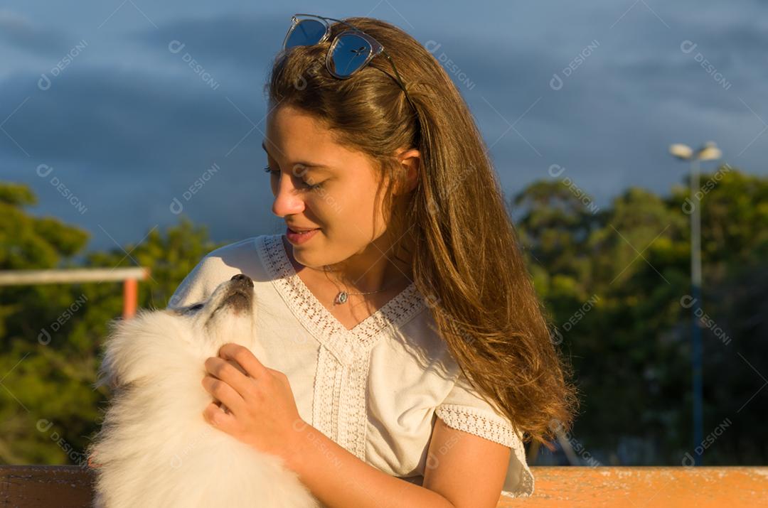 Jovem mulher bonita brincando com cachorro Spitz alemão no parque de verão
