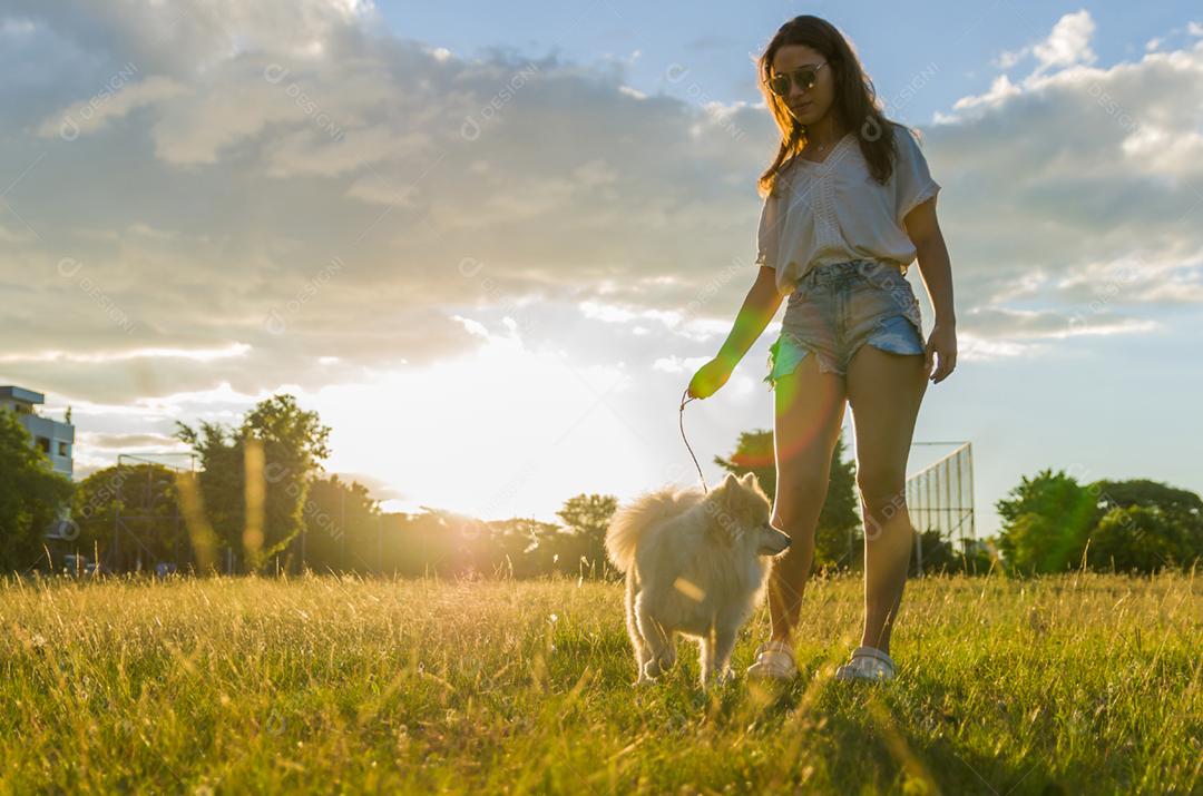 Jovem mulher bonita brincando com cachorro Spitz alemão no parque de verão