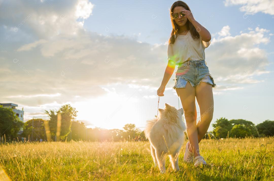 Jovem mulher bonita brincando com cachorro Spitz alemão no parque de verão