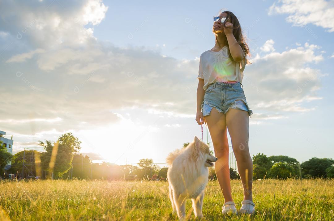 jovem mulher bonita brincando com cachorro Spitz alemão no parque de verão