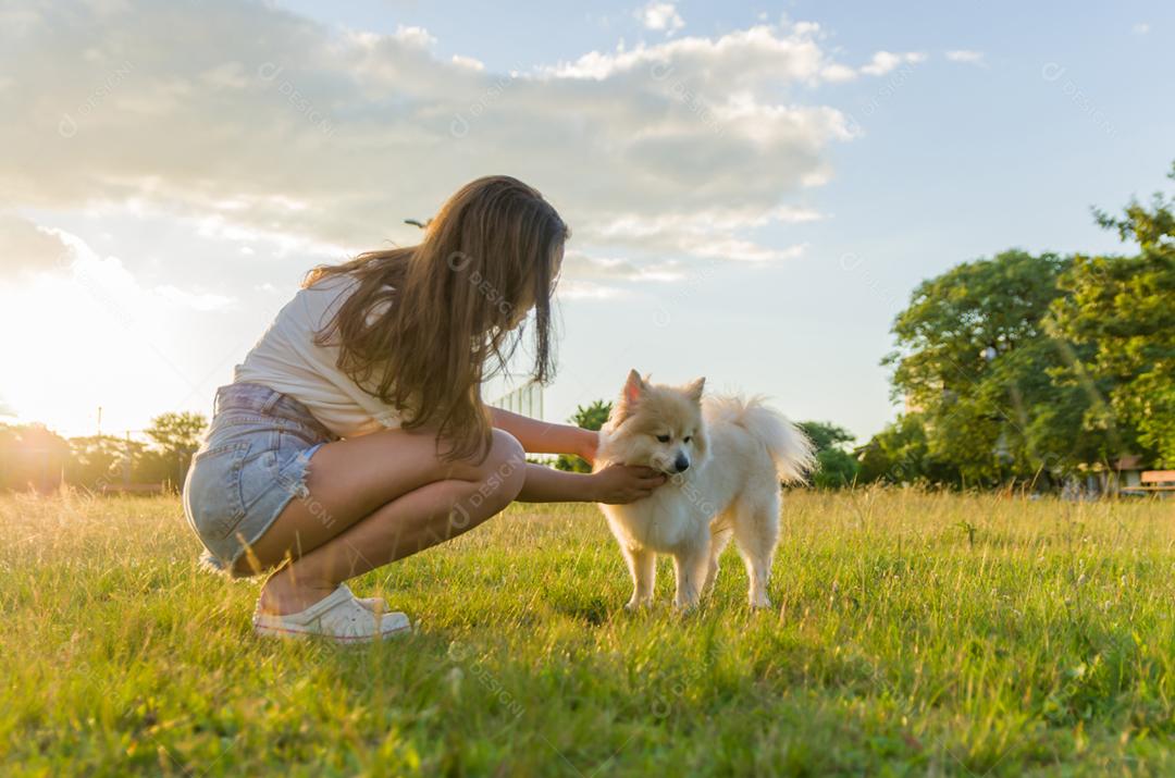 jovem mulher bonita brincando com cachorro Spitz alemão no parque de verão