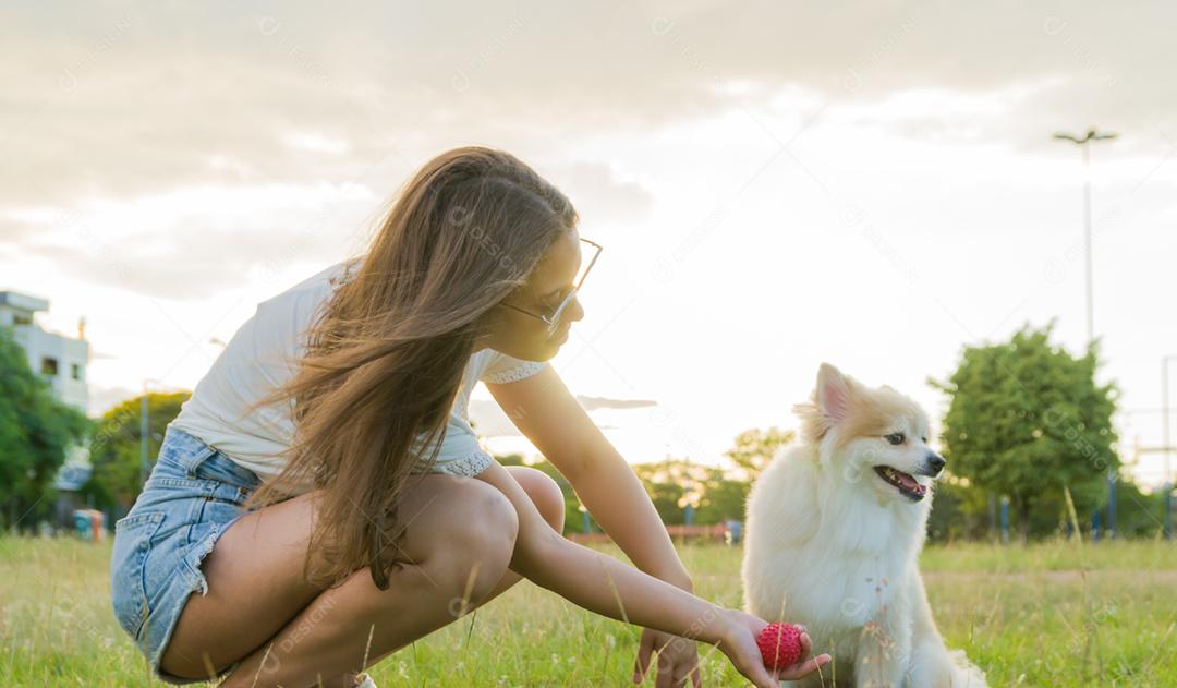 jovem mulher bonita brincando com cachorro Spitz alemão no parque de verão
