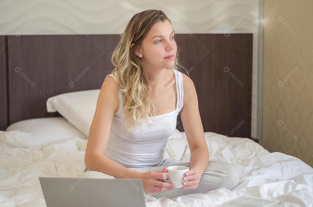 Jovem mulher loira pensativa na cama, acordando.