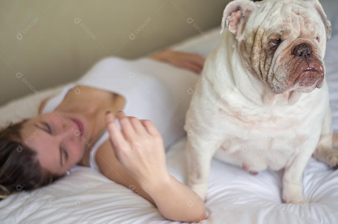 Linda mulher dormindo na cama com cachorro bulldog inglês.