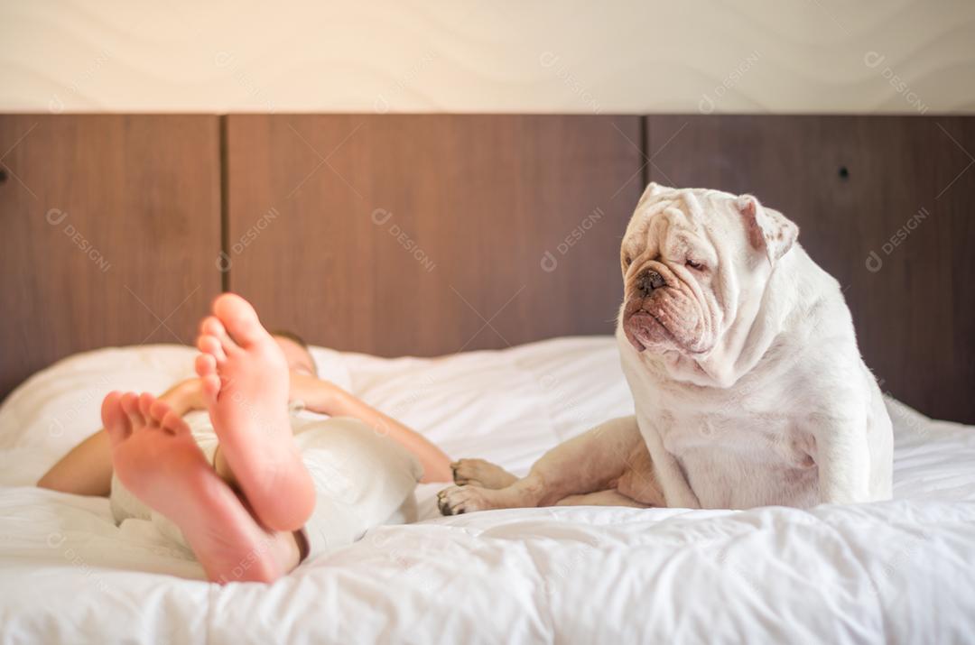 Linda mulher dormindo na cama com cachorro bulldog inglês. Somente os pés.