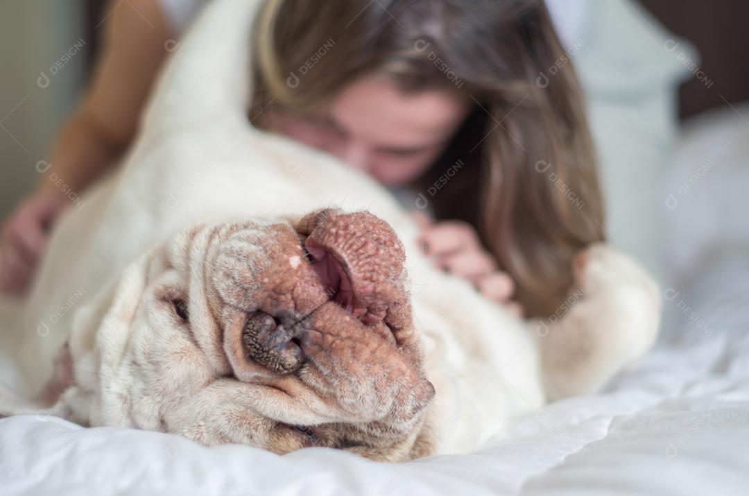 Linda mulher dormindo na cama com cachorro bulldog inglês.