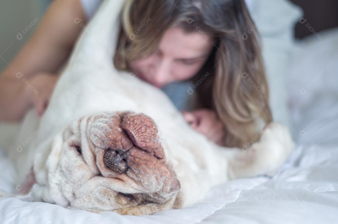 Linda mulher dormindo na cama com cachorro bulldog inglês.