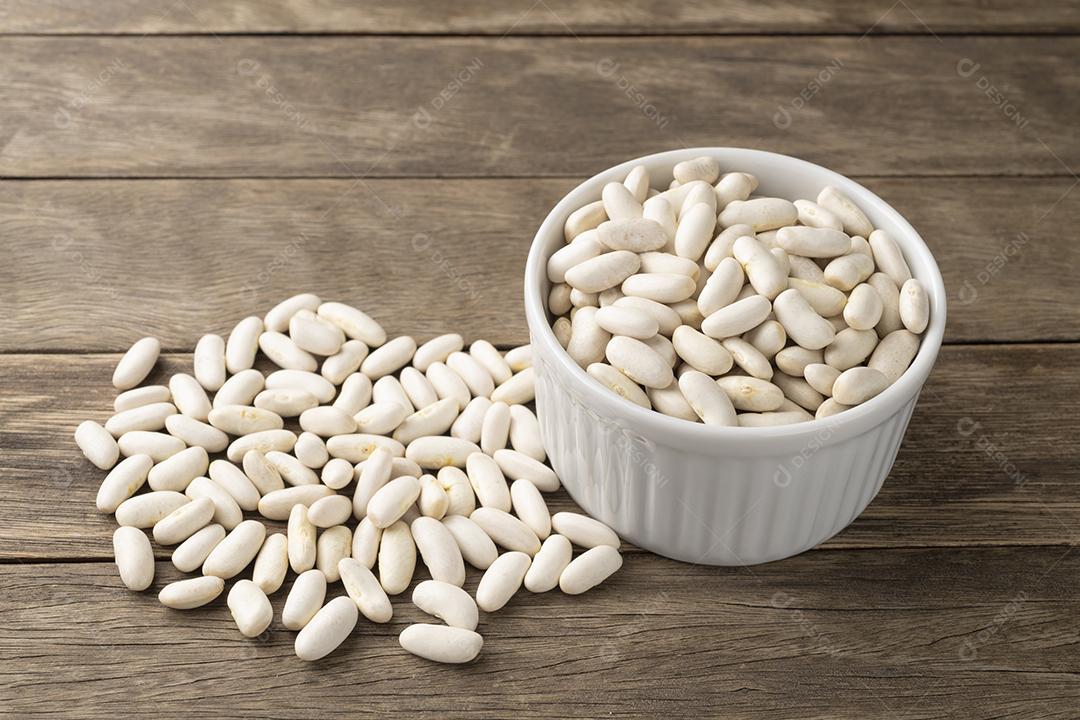 Feijão branco em uma tigela sobre mesa de madeira.