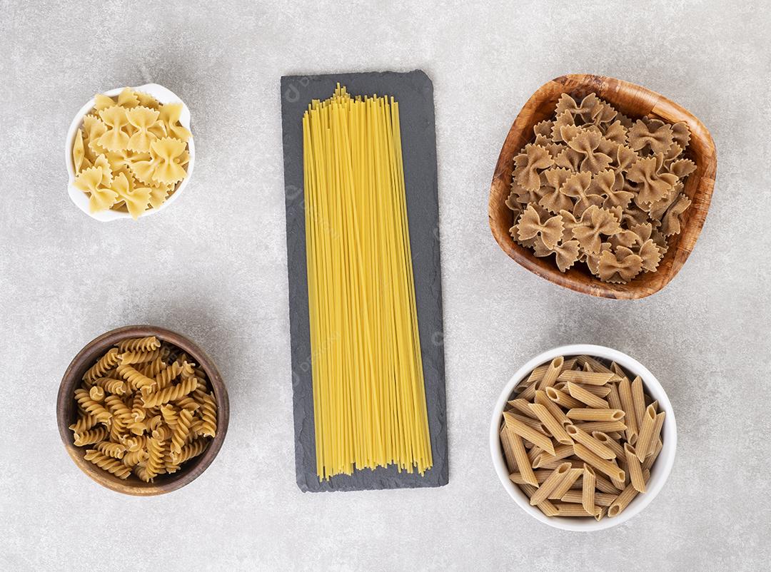 Espaguete, farfalle, fusilli e macarrão penne sobre a contagem de concreto
