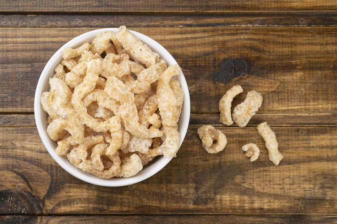 Torres de porco fritos em uma tigela branca sobre mesa de madeira.
