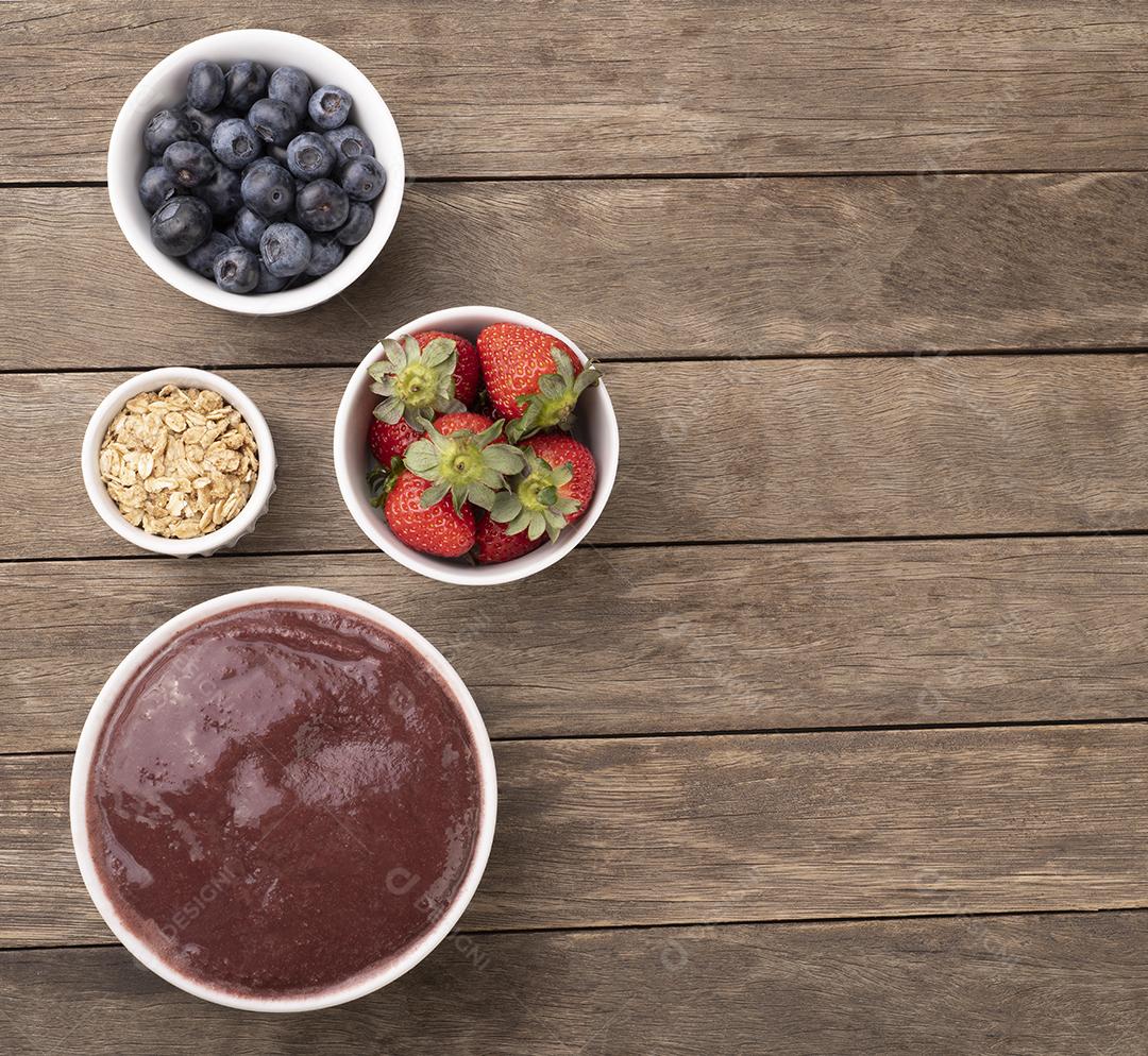 Tigela típica de açaí brasileira com frutas e muesli sobre fundo de madeira